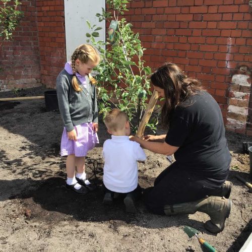 Phoebe and Corey planting a tree